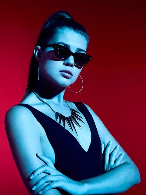 Nahaufnahme mit rotem Hintergrund von einem Female Model, das eine Shamballa Sonnenbrille trägt.