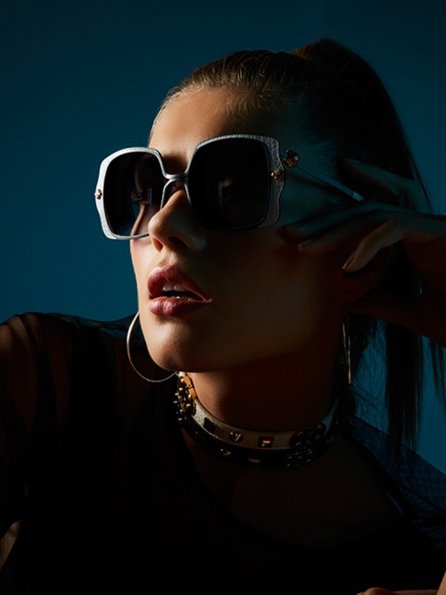 Dunkelblaue Aufnahme von einem Female Model, das eine Shamballa Sonnenbrille trägt.