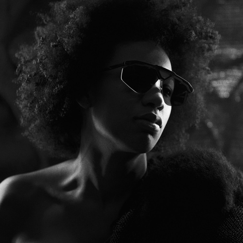 Schwarz-weiße Nahaufnahme von einem weiblichen Model, das eine Ralph Vaessen schwarze Sonnenbrille trägt.