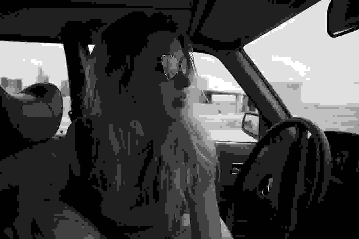 Eine blonde Frau posiert mit einer Ahlem Fassung auf dem Fahrersitz in einem Auto.