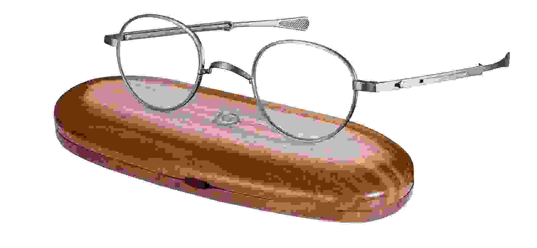 Nahaufnahme von einer Gernot Lindner runden Korrekturbrille mit silbernem Gestell, die auf einem Brillenetui aus Holz liegt.
